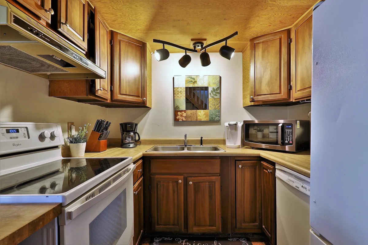 This image spotlights the cabin's fully-equipped kitchen, complete with warm wood cabinetry, modern appliances, and tasteful wall art. The space is set up for cooking, baking, and hosting, reflecting the promise of a Keurig for morning coffee and all essentials for family feasts.
