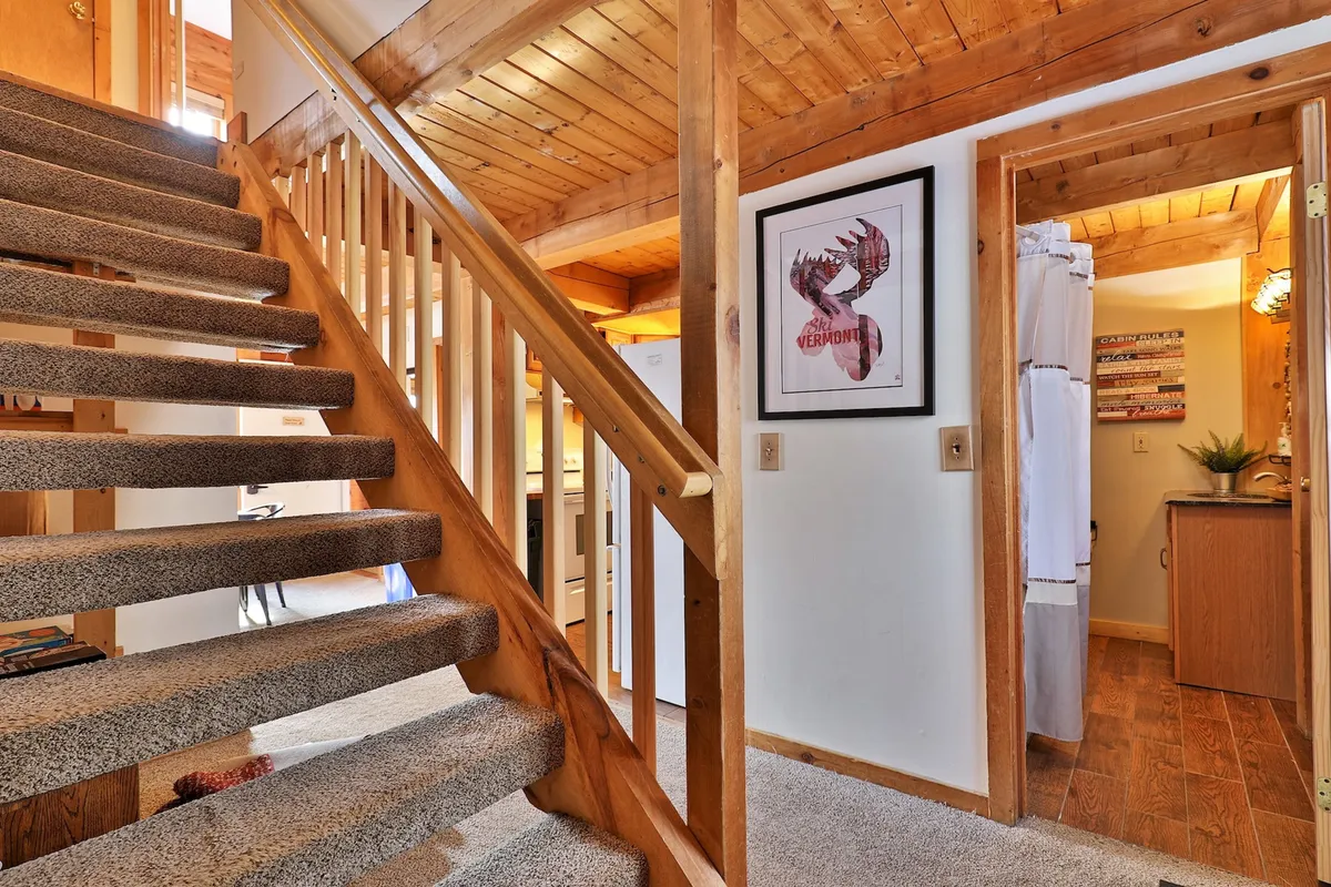This image highlights an interior view of a cozy staircase and an entryway, featuring artwork on the wall and a doorway leading into another room. The space feels inviting and functional, with clear passage for guests as they come and go, and hints at convenient access throughout the home.