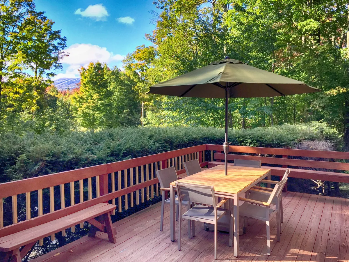 An outdoor dining area with a table and umbrella showcases relaxing communal space with a mountain view in the background. While not specifically wintery, the expansive vista connects the property to the surrounding outdoors and hints at year-round enjoyment, including gathering after a day on the slopes.